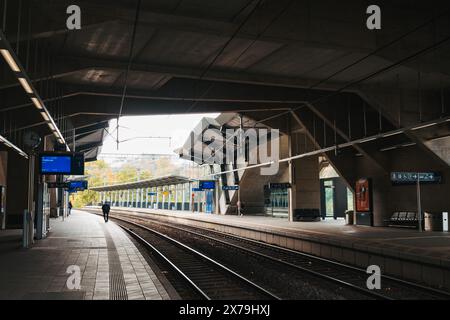 Leere Gleise kurven durch den modernen Bahnhof Pfaffenthal-Kirchberg in Luxemburg-Stadt, eingerahmt von geometrischer Betonarchitektur und klaren Bahnsteigen Stockfoto
