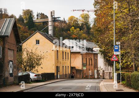 Ruhige Vorstadtstraße im Stadtteil Pfaffenthal der Stadt Luxemburg mit Herbstlaub, historischen Häusern und dem Panoramablick-Aufzug dahinter Stockfoto