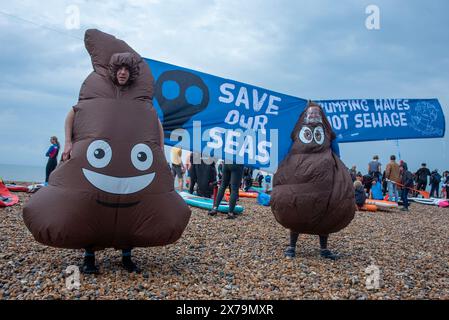 Brighton, Großbritannien. Mai 2024. Als Kot gekleidete Demonstranten stehen während der Demonstration am Brighton Beach vor den Spruchbändern. Surfer gegen Abwasser organisierten einen nationalen Protest im ganzen Land, um gegen die Wassergesellschaften zu kämpfen, die Abwasser in die britischen Flüsse und Meere dämpften. Surfer, Taucher, Paddelboarder und Schwimmer nahmen an der Demonstration in Brighton, Großbritannien, Teil. Quelle: SOPA Images Limited/Alamy Live News Stockfoto