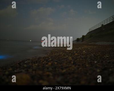 Sheerness, Kent, Großbritannien. Mai 2024. Wetter in Großbritannien: Atemberaubend lebendige, leuchtend blaue Biolumineszenz, die heute Abend am Sheerness Beach in Kent zu sehen ist - die Farbe entsteht, wenn biolumineszierendes Plankton gestört wird. Bilder zeigen Wellen und Steine, die ins Meer geworfen wurden. Quelle: James Bell/Alamy Live News Stockfoto