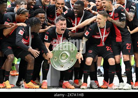 Leverkusen, Deutschland. Mai 2024. Granit Xhaka (C, Front) von Bayer 04 Leverkusen hält die Trophäe während der Siegerehrung des Titels der Bundesliga in Leverkusen am 18. Mai 2024. Quelle: Ulrich Hufnagel/Xinhua/Alamy Live News Stockfoto