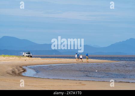 Das Fahrzeug parkte am Strand und vier Personen laufen am Sandstrand, Macquarie Heads, Westküste Tasmanien Stockfoto