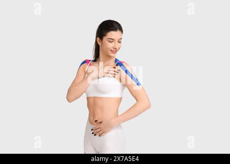 Schöne junge Frau mit Physioband auf weißem Hintergrund Stockfoto