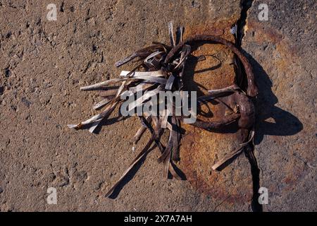 Ein rostiger Metallanlegerring hat rostige Spuren auf dem Beton hinterlassen, in den er eingebettet ist. Überreste von getrockneten Algen hängen auf dem Metall. Seebrücke, Sommer, Stockfoto