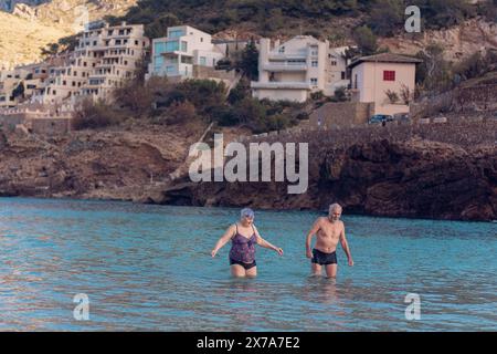 Alte Leute schwimmen im Meer. Ein älteres Paar genießt das Leben, indem es Zeit auf See verbringt. Ein alter Großvater und eine Großmutter im Badeanzug gehen entlang Stockfoto