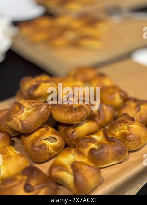 Nahaufnahme von frisch gebackenem Gebäck auf einem Holzbrett. Goldbraun und köstlich, perfekt zum Frühstück oder für einen Snack. Stockfoto