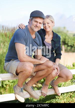 Glückliches, reifes Paar und sitzt auf einem Bauernzaun im Weinberg in Italien, um sich in der Natur zu unterhalten. Lächeln, Seniorinnen und Senioren auf dem Land Stockfoto