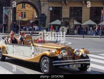 Prag, Tschechische Republik - 10. Mai 2024: Touristen fahren in einem offenen Cabrio, im Stil eines alten Timers, auf dem Platz vor dem Pulverturm entlang Stockfoto