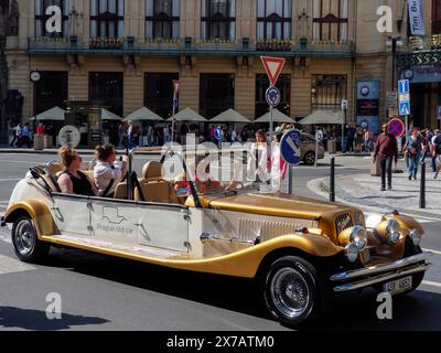 Prag, Tschechische Republik - 10. Mai 2024: Touristen fahren in einem offenen Cabrio, im Stil eines alten Timers, auf dem Platz vor dem Pulverturm entlang Stockfoto