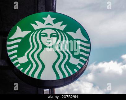 Prag, Tschechische Republik - 10. Mai 2024: Ein leuchtend grünes Starbucks Coffee Shop-Schild mit dem ikonischen Meerjungfrauenlogo ist deutlich vor einem abgebildet Stockfoto