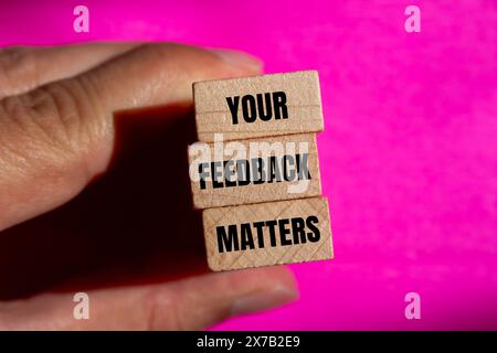 Ihr Feedback ist wichtig, dass Wörter auf Holzblöcken mit rosafarbenem Hintergrund geschrieben werden. Konzeptionell ist das Symbol „Ihr Feedback zählt“. Kopierbereich. Stockfoto