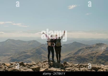 Zwei Frauen erreichen neue Höhen der Freude, der Freiheit und des Erfolgs auf dem Scenic Peak of Ben Nevis, umgeben von atemberaubenden Berglandschaften Stockfoto