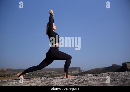 Eine Frau macht Yoga auf einem felsigen Hügel Stockfoto