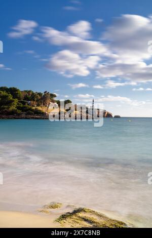 Blick auf den Strand Arenal Dets ASEs und den Leuchtturm von Portocolom im Hintergrund Stockfoto
