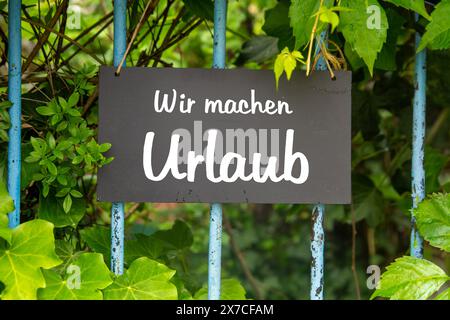 Symbolbild für Firmenferien: Schild auf dem Garten mit der deutschen Aufschrift wir MACHEN URLAUB (wir sind im Urlaub) Stockfoto