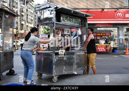 (240519) -- CHANGSHA, 19. Mai 2024 (Xinhua) -- Zhang Yongsheng (R) verlegt seinen Imbissstand auf dem Sifangping Nachtmarkt in Changsha, zentralchinesischer Provinz Hunan, 15. Mai 2024. Obwohl sie hörgeschädigt waren, gelang es Zhang Yongsheng und seiner Frau Zhan Jingwen, ihre Tochter, die ebenfalls an der gleichen Behinderung leidet, im Alter von zwei Jahren zu hören. Durch einen Imbissstand auf einem Nachtmarkt und dank der Unterstützung ihrer Verwandten und Freunde gelang es dem Paar, sich ein Cochlea-Implantat für das linke Ohr ihrer Tochter und ein Hörgerät für das rechte Ohr ihrer Tochter zu leisten. „Es ist zu teuer, die zu haben Stockfoto