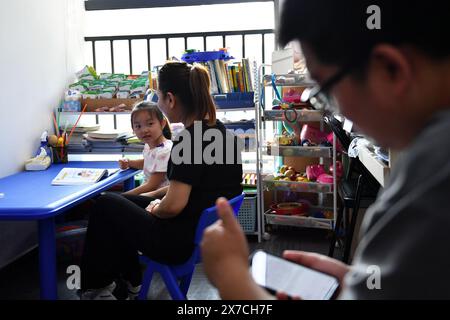 (240519) -- CHANGSHA, 19. Mai 2024 (Xinhua) -- Tochter Zhang Yuhan (L) besucht eine Klasse in Begleitung seines Vaters Zhang Yongsheng (R) in einem Kinderentwicklungszentrum in Changsha, zentralchinesischer Provinz Hunan, 17. Mai 2024. Obwohl sie hörgeschädigt waren, gelang es Zhang Yongsheng und seiner Frau Zhan Jingwen, ihre Tochter, die ebenfalls an der gleichen Behinderung leidet, im Alter von zwei Jahren zu hören. Durch einen Imbissstand auf einem Nachtmarkt und dank der Unterstützung ihrer Verwandten und Freunde gelang es dem Paar, sich ein Cochlea-Implantat für das linke Ohr ihrer Tochter und ein Hörgerät für die Tochter zu leisten Stockfoto