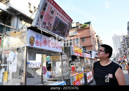 (240519) -- CHANGSHA, 19. Mai 2024 (Xinhua) -- Zhang Yongsheng schaut auf das Schild an seinem Imbissstand auf dem Sifangping Nachtmarkt in Changsha, zentralchinesischer Provinz Hunan, 15. Mai 2024. Er hat das Wort „geräuschlos“ auf dem Schild in „hörbar“ geändert, nachdem sein Cochlea-Implantat eingeschaltet und behoben wurde. Obwohl sie hörgeschädigt waren, gelang es Zhang Yongsheng und seiner Frau Zhan Jingwen, ihre Tochter, die ebenfalls an der gleichen Behinderung leidet, im Alter von zwei Jahren zu hören. Durch den Betrieb eines Imbissstandes auf einem Nachtmarkt und dank der Unterstützung durch ihre Verwandten und Freunde schaffte es das Paar Stockfoto