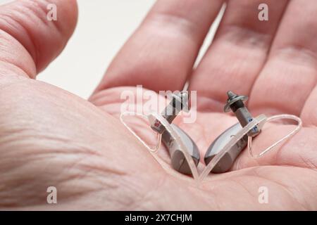 Nahaufnahme eines kleinen diskreten Hörgerätes in einer männlichen Hand Stockfoto