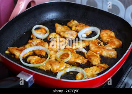 Hähnchenfilet mit Grillsoße und gehackten Zwiebeln in einer Pfanne kochen Stockfoto