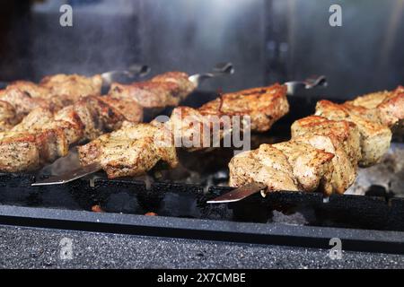 Kebabs auf Spießen, Nahaufnahme. Food Court auf der Messe, Outdoor Cooking. Warmes und leckeres Essen. Koche Schaschlik auf Kohlen. Gegrillter Kebab, gekocht auf einem Meta Stockfoto