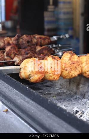 Kebabs auf Spießen, Nahaufnahme. Food Court auf der Messe, Outdoor Cooking. Warmes und leckeres Essen. Koche Schaschlik auf Kohlen. Gegrillter Kebab, gekocht auf einem Meta Stockfoto