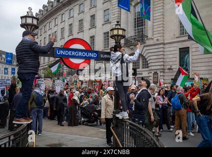 London, Großbritannien. 18. Mai 2024: Menschen stehen auf Geländern an der U-Bahn-Station Piccadilly Circus, um Demonstranten beim Nakba-Marsch 76 für Palästina wieder zu fotografieren Stockfoto