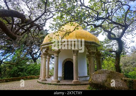 Der Säulentempel mit einer gelben Kuppel, die von zwölf Säulen gehalten wird, im Park rund um den Pena-Palast oder das historische Schloss Palácio da Pena in Sintra, Portugal. Der märchenhafte Schlosspalast gilt als eines der schönsten Beispiele der portugiesischen Romantik des 19. Jahrhunderts der Welt. Stockfoto