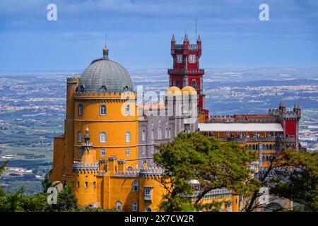 Der Pena-Palast oder das historische Schloss Palácio da Pena vom Hochkreuz in Sintra, Portugal. Der märchenhafte Schlosspalast gilt als eines der schönsten Beispiele der portugiesischen Romantik des 19. Jahrhunderts der Welt. Stockfoto