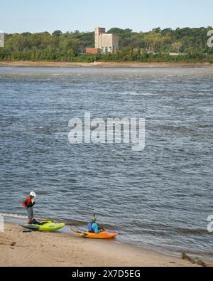 Granite City, Il, USA – 8. Oktober 2023: Zwei Kajakfahrer starten Wildwasserkajaks von einem Strand am Mississippi River unterhalb eines Wassers des Low W Stockfoto