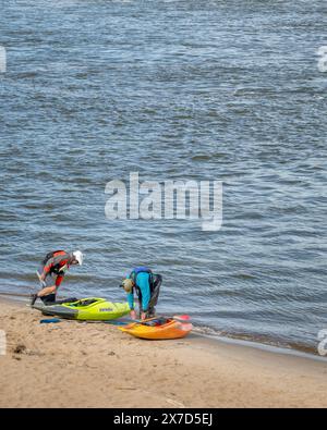 Granite City, Il, USA – 8. Oktober 2023: Zwei Kajakfahrer starten Wildwasserkajaks von einem Strand am Mississippi River unterhalb eines Wassers des Low W Stockfoto