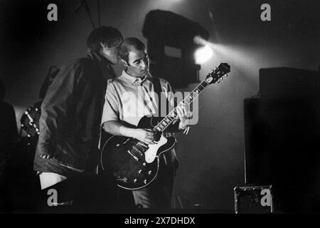 LIAM, BONEHEAD, OASIS, FIRST GLASTONBURY HEADLINE, 1995: Liam Gallagher und Bonehead (Paul Arthurs) von Oasis Headline teilen einen Moment während des Encore auf der Main Stage auf dem Höhepunkt ihrer Berühmtheit beim Glastonbury Festival, Pilton Farm, Somerset, England, 24. Juni 1995. 1995 feierte das Festival sein 25-jähriges Bestehen. In diesem Jahr gab es keine Pyramidenphase, da sie abgebrannt war. Foto: ROB WATKINS Stockfoto