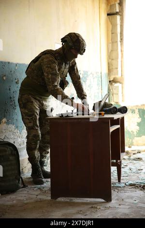 Militärische Mission. Soldat in Uniform mit Laptop am Tisch im verlassenen Gebäude Stockfoto