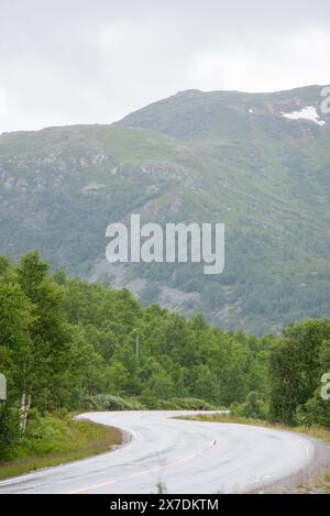 Gewundene Bergstraße in Norwegen mit Blick auf große Fjorde an einem nebeligen, regnerischen Sommertag. Stockfoto