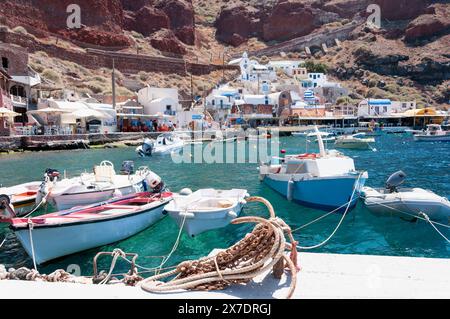 Malerischer Hafen von Ammoudi auf der Insel Santorin in Griechenland, mit seinen Fischerbooten, dem blauen Wasser und den steilen Klippen Stockfoto