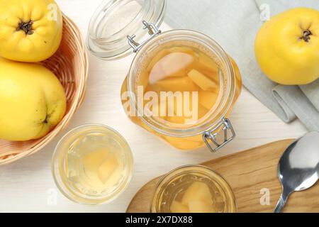 Köstliches Quittengetränk, frisches Obst und Löffel auf weißem Holztisch, flach gelegen Stockfoto