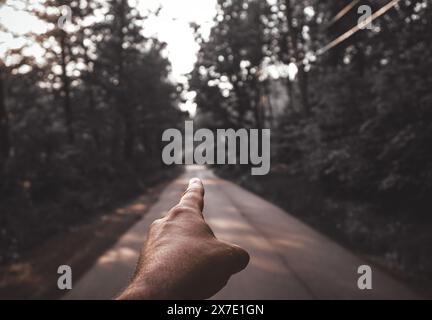 Zugeschnittene Hand, die auf eine Straße zeigt Stockfoto