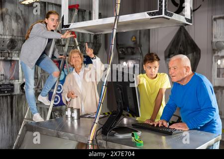 Großeltern und Enkelkinder, die sich im Fluchtzimmer mit einem Konundrommel herumtoben Stockfoto