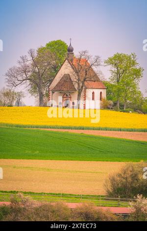 Eine idyllische Kapelle umgeben von blühenden Feldern und Bäumen, umrahmt von einem blauen Himmel mit weichen Wolken, Frühling, Neuhausen, Schwarzwald, Deutschland Stockfoto