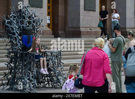 Kiew, Ukraine. Mai 2024. Ein Mann fotografiert ein Kind, das während der russischen Invasion in der Ukraine auf dem ìThrone des Winnerî im Zentrum von Kiew sitzt. Die Installation besteht aus ca. 200 Metalldrohnen. Das Gewicht des Throns beträgt etwa 350ñ400 kg bei einer Höhe von 2,7 Metern. ìThrone des Winnerî wird in Kiew und dann in anderen Städten der Ukraine gezeigt. Die Anlage wird versteigert, und die Einnahmen werden für den Kauf von Kampfdrohnen verwendet. Quelle: SOPA Images Limited/Alamy Live News Stockfoto