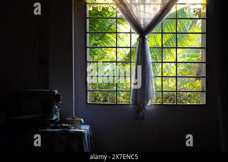 Am frühen Morgen auf der vietnamesischen Landschaft, Schlafzimmer mit Sonnenlicht, Fenster mit Blick auf den Garten, Moskitonetz mit Schatten machen romantisches Bett, einfaches Zimmer in Stockfoto