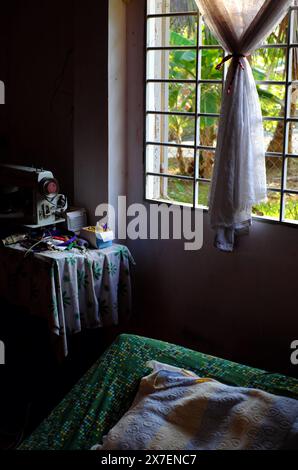 Am frühen Morgen auf der vietnamesischen Landschaft, Schlafzimmer mit Sonnenlicht, Fenster mit Blick auf den Garten, Moskitonetz mit Schatten machen romantisches Bett, einfaches Zimmer in Stockfoto