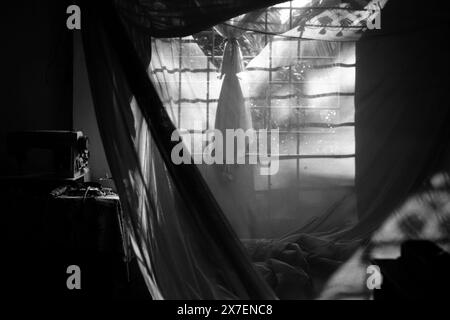 Am frühen Morgen auf der vietnamesischen Landschaft, Schlafzimmer mit Sonnenlicht, Fenster mit Blick auf den Garten, Moskitonetz mit Schatten machen romantisches Bett, einfaches Zimmer in Stockfoto