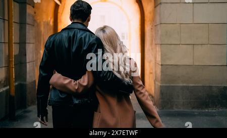 Ein paar zu Fuß. Romantisch im Freien. Rückansicht eines nicht erkennbaren Mannes bei einem Date mit einer blonden Freundin, die zusammen schlendert und sich auf der städtischen Straße umgibt. Stockfoto