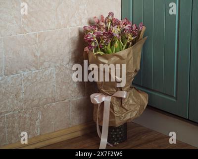 Horizontale Nahaufnahme eines Straußes verblasster rosa Tulpen in einer Vase auf dem Boden in der Küchenecke. Stockfoto