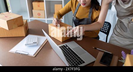 Asiatische Frauen, die Versandlogistik für Online-Geschäfte verwalten. Konzept für E-Commerce-Vorgänge, Teamarbeit und Auftragsabwicklung Stockfoto