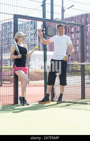 Porträt von zwei lächelnden Sportlern, die auf dem Padel-Platz im Freien mit Schlägern posieren - Padel-Spieler Stockfoto
