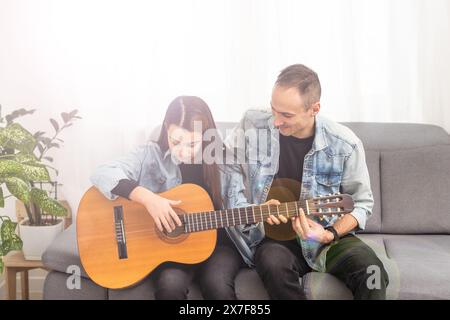 Der Gitarrenlehrer unterrichtet das kleine Mädchen Stockfoto