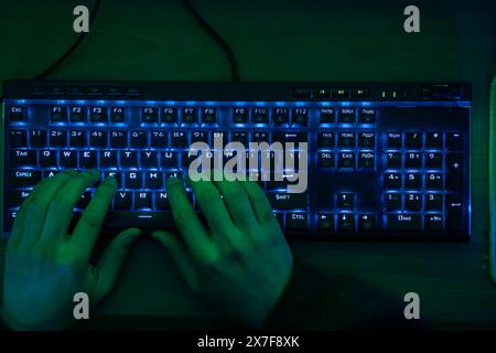 Close-up auf der Gamer Hände auf der Tastatur, Tasten, Spielen MMO-Spiele Online. Hintergrund Leuchtet mit Neonlicht. Stockfoto