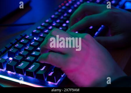 Close-up auf der Gamer Hände auf der Tastatur, Tasten, Spielen MMO-Spiele Online. Hintergrund Leuchtet mit Neonlicht. Stockfoto